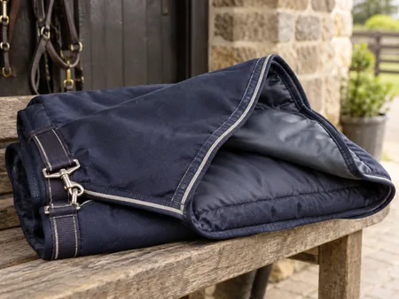 Close view of a folded navy horse rug on a bench.
