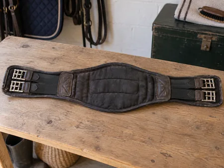 A second-hand padded horse girth opened flat showing its underside.