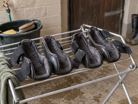 Open horse brushing boots rinsed and resting lining-side upward on a drying rack.